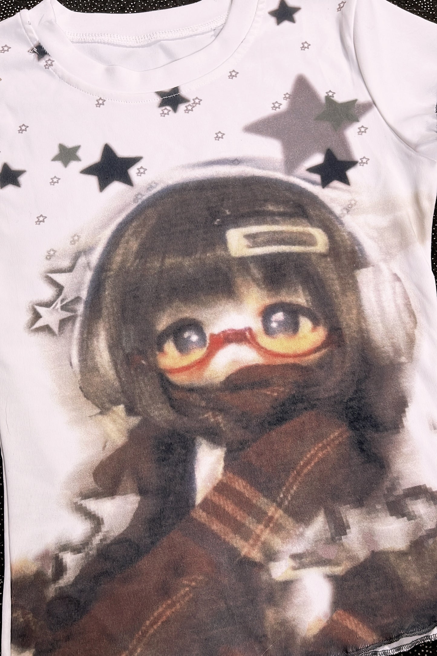 White graphic T-shirt close-up with character face portrait and star accents