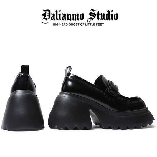 Black platform loafers with rounded toe, chunky sole, and strap-style detail