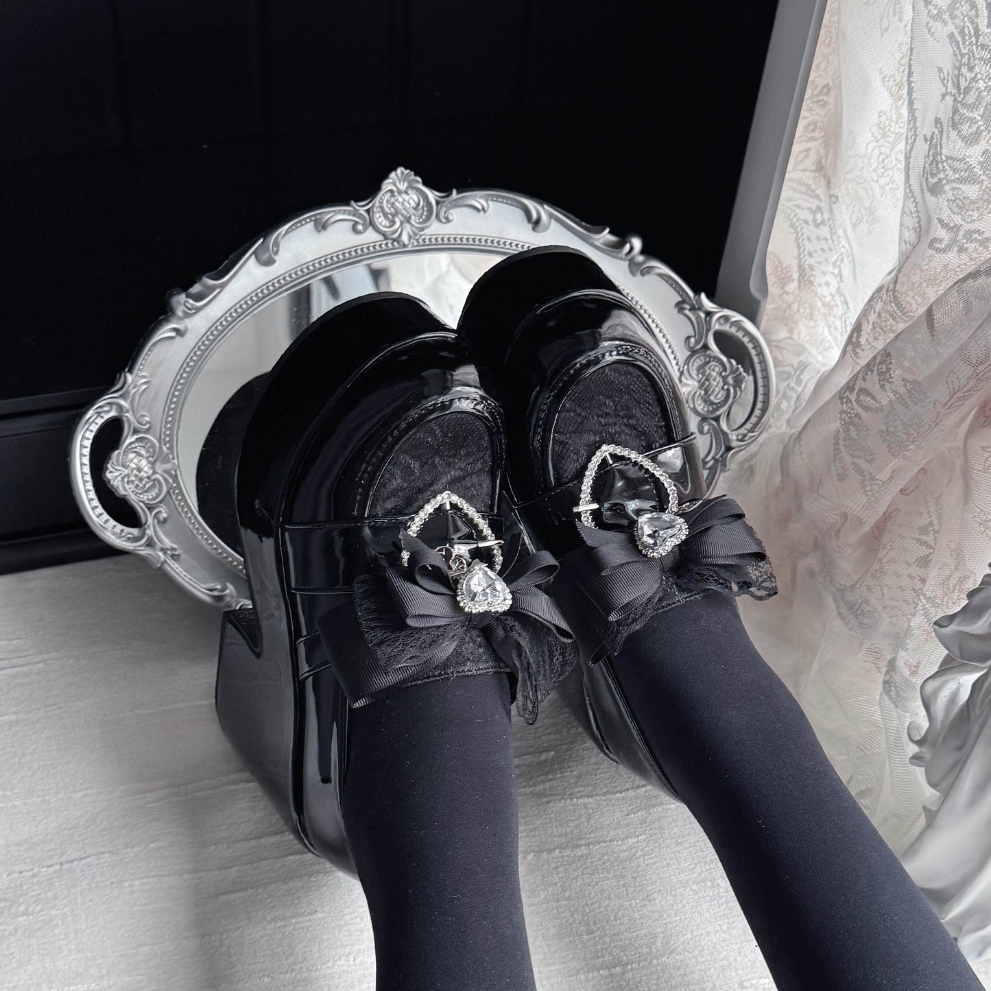 Black platform loafers with ribbon bow and heart charm, glossy finish and lace panels
