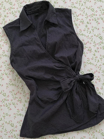 Black sleeveless cardigan top with V-neck front and tied waist bow, flared hem