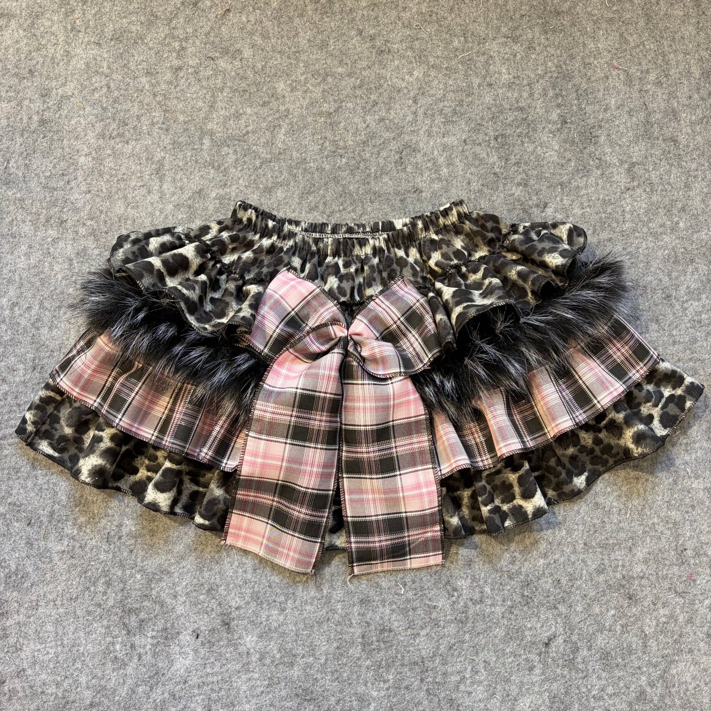 Puffy mini skirt with leopard print and pink plaid layers, faux fur trim and central bow
