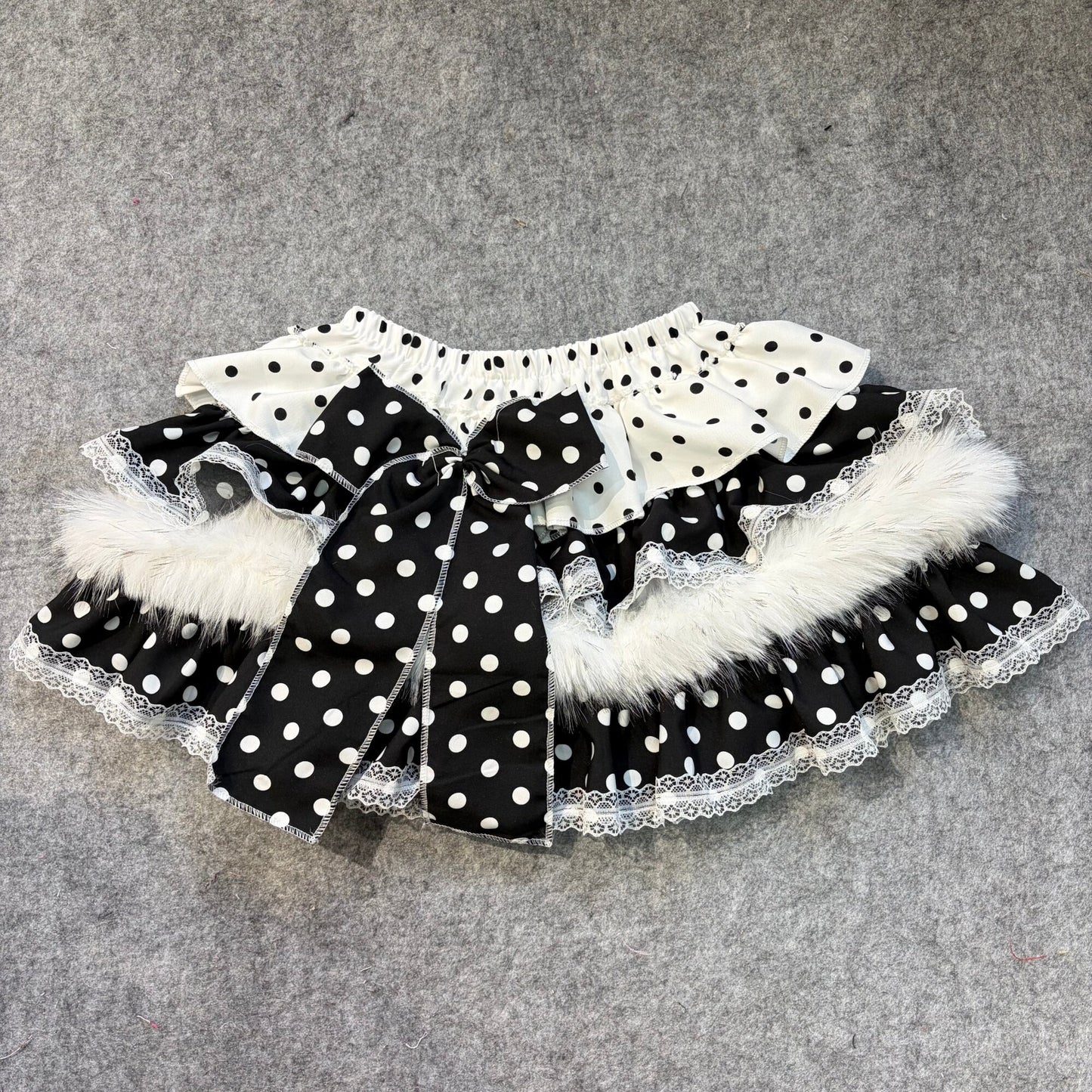 Black puffy mini skirt with white polka-dot top ruffle, lace trim, faux fur accents and bow