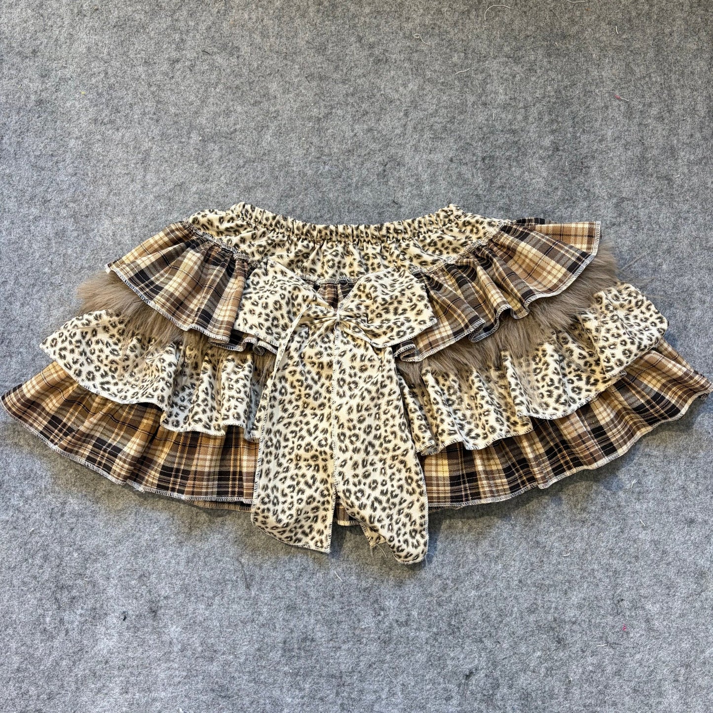 Puffy mini skirt in leopard print and plaid panels with layered ruffles and tied bow