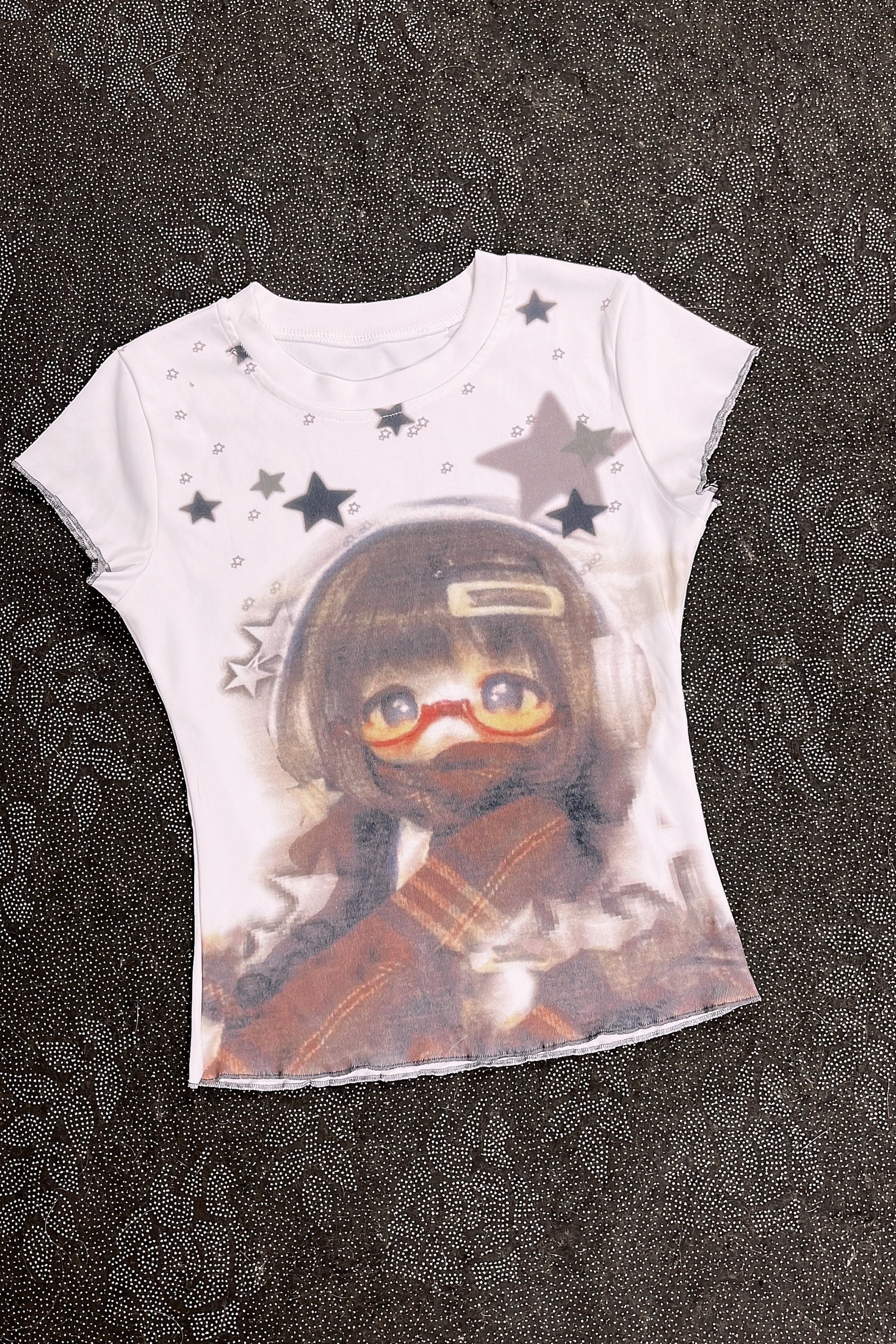 White graphic T-shirt with character portrait, scattered stars, and short sleeves