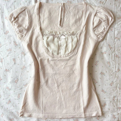 Cream camisole top with rounded neckline, short puff sleeves, button placket detail