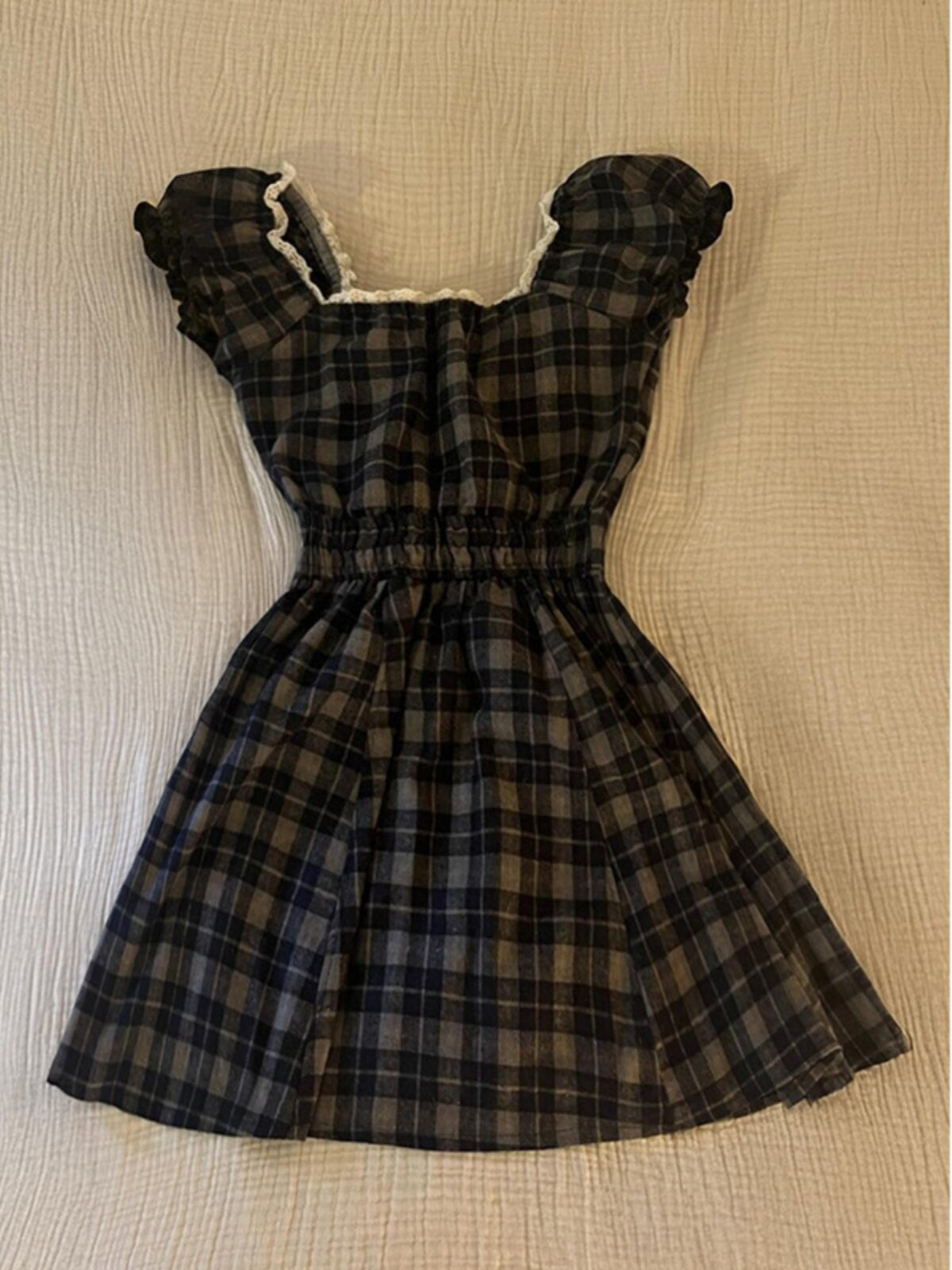 Plaid square-neck dress with puff sleeves and gathered skirt; cream ruffle trim at neckline.