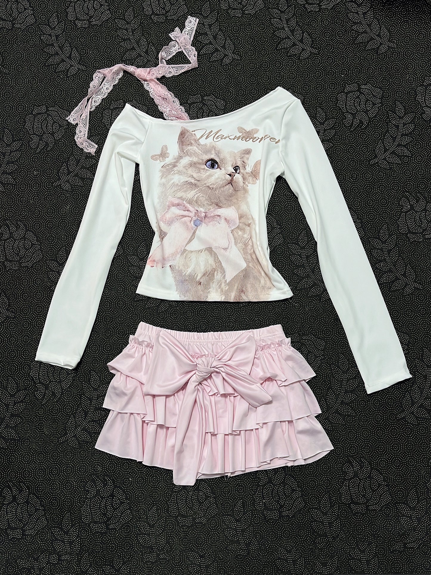Cream long-sleeve top with cat graphic, lace-trim strap, and layered pink ruffle skirt