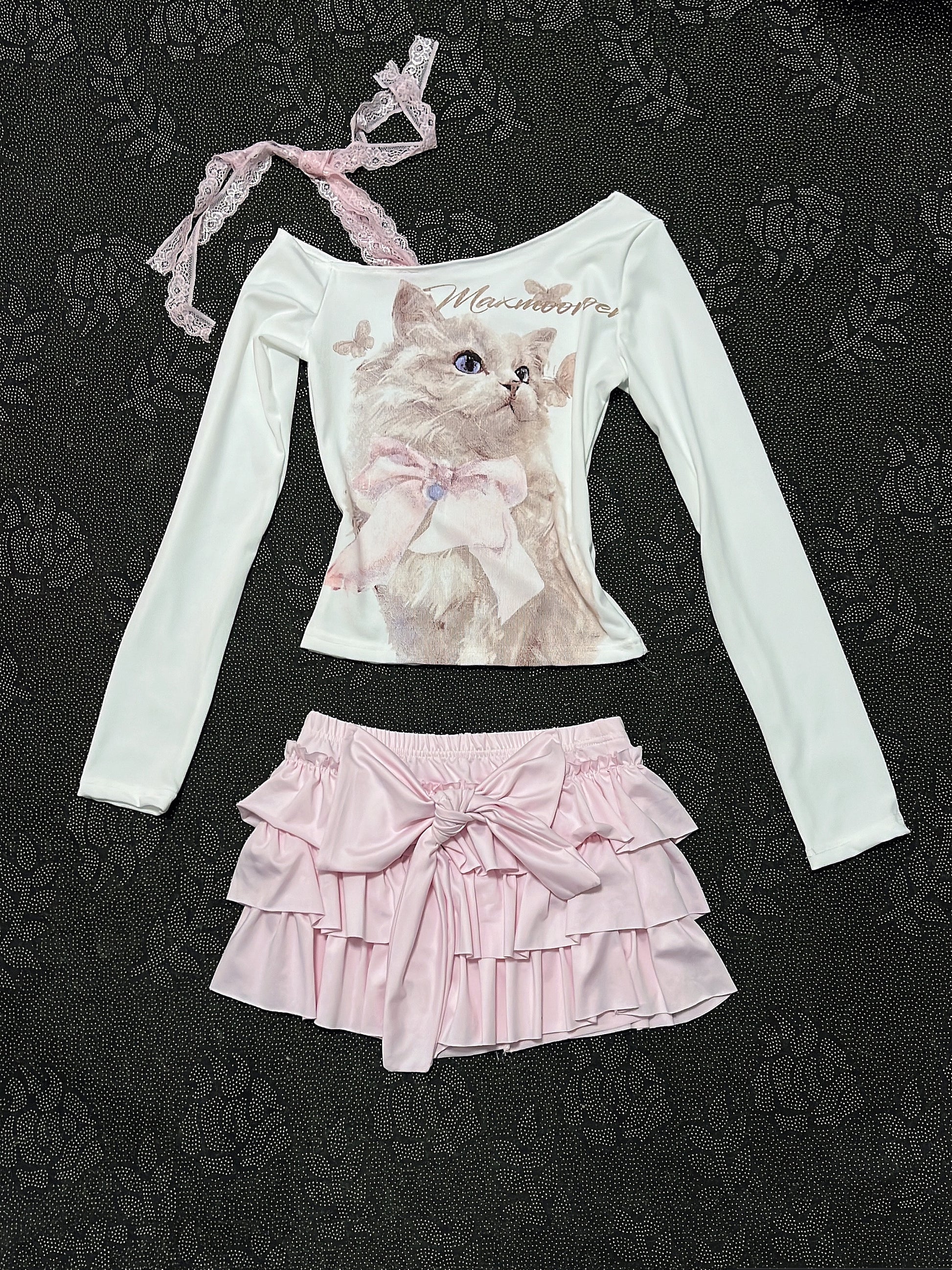 Cream long-sleeve top with cat graphic, lace-trim strap, and layered pink ruffle skirt