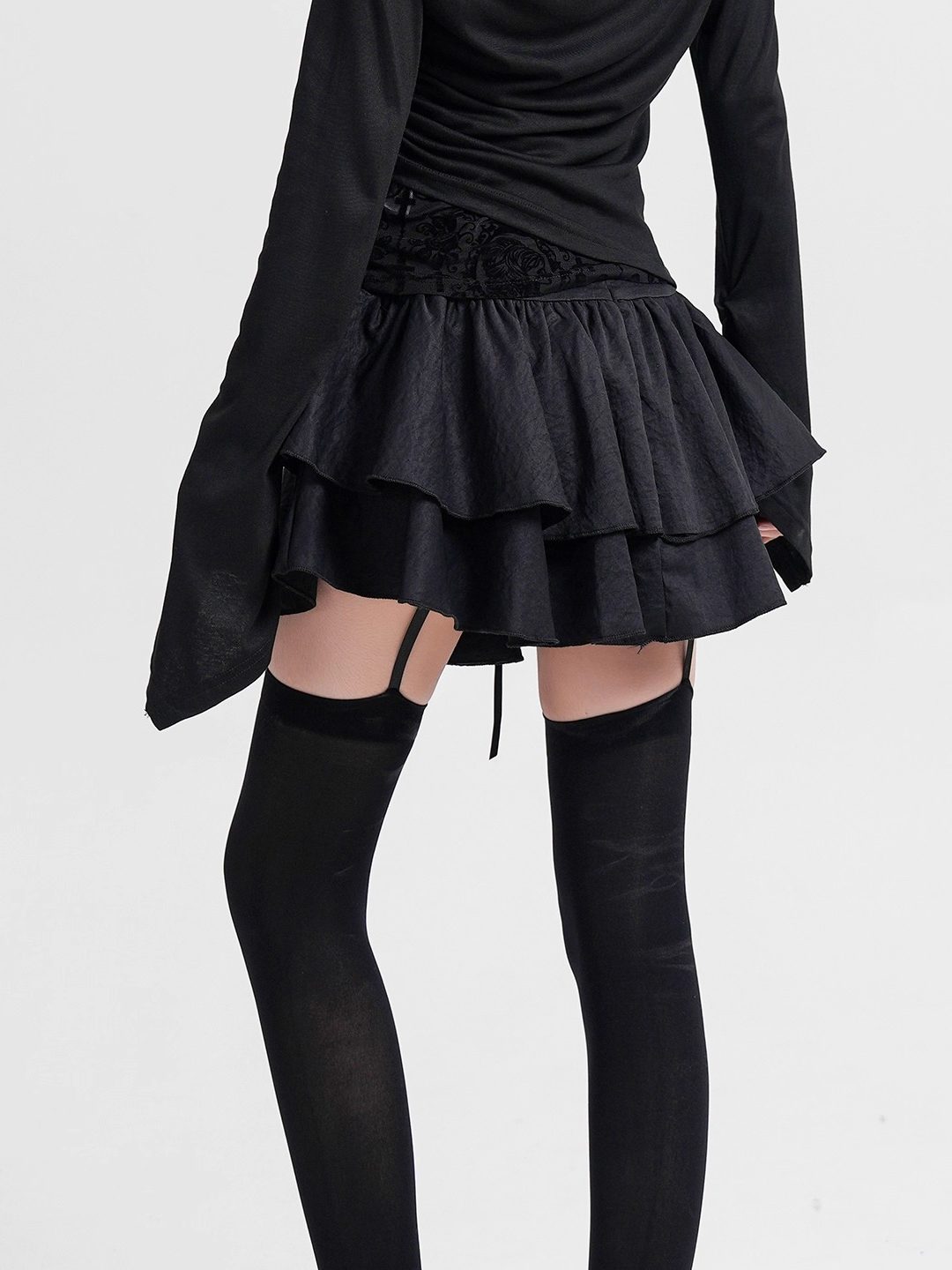 Black mini cake skirt with gathered ruffle tiers and lace-up belt ties at the waist.