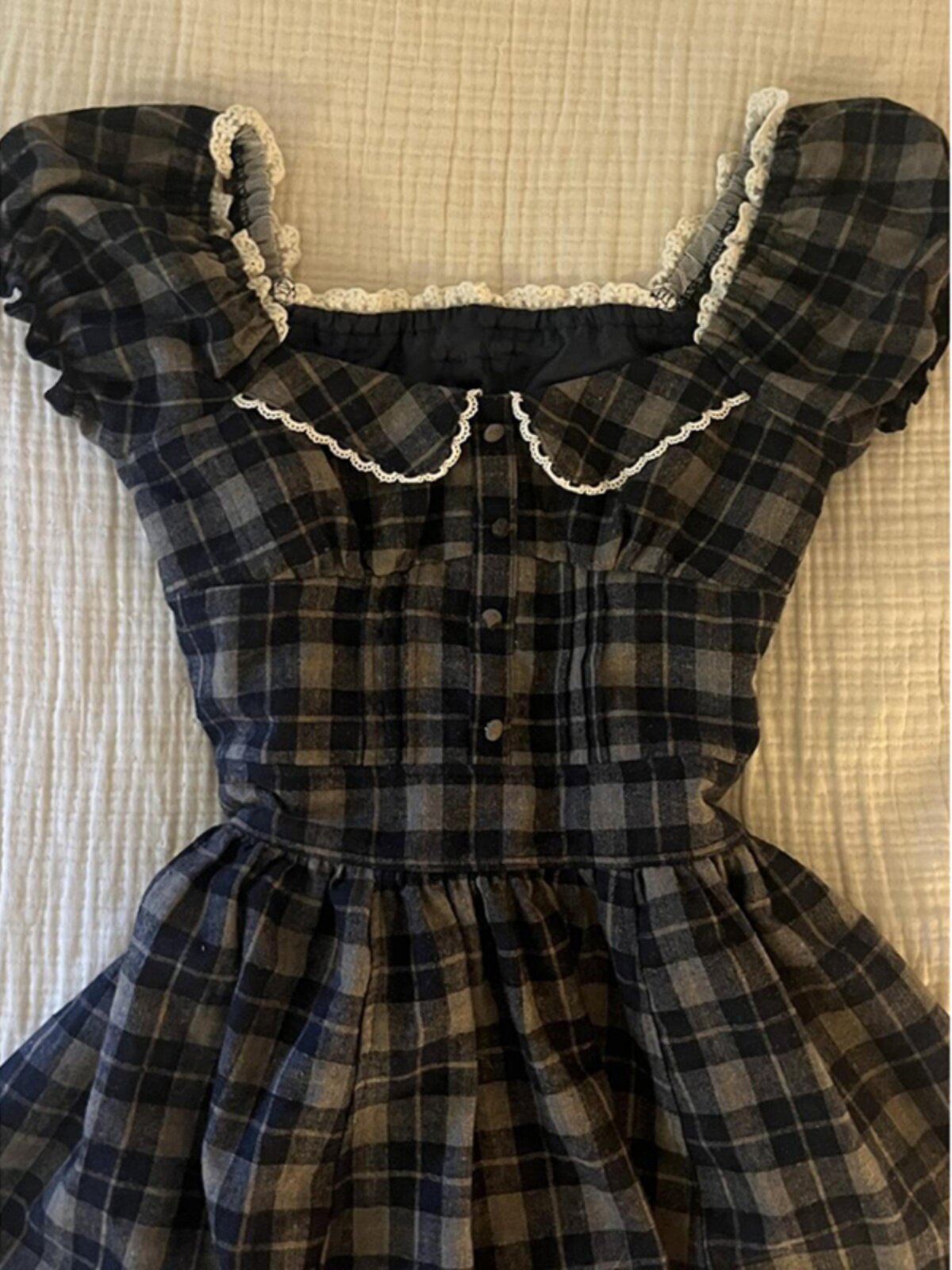 Plaid square-neck dress with puff sleeves, cream ruffle trim, and gathered waist skirt flare.