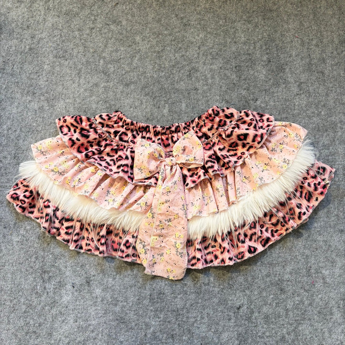 Puffy mini skirt in leopard print with light floral accents, faux fur trim and bow