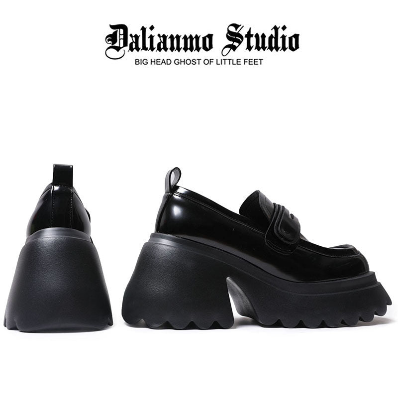 Black platform loafers with rounded toe, chunky sole, and strap-style detail