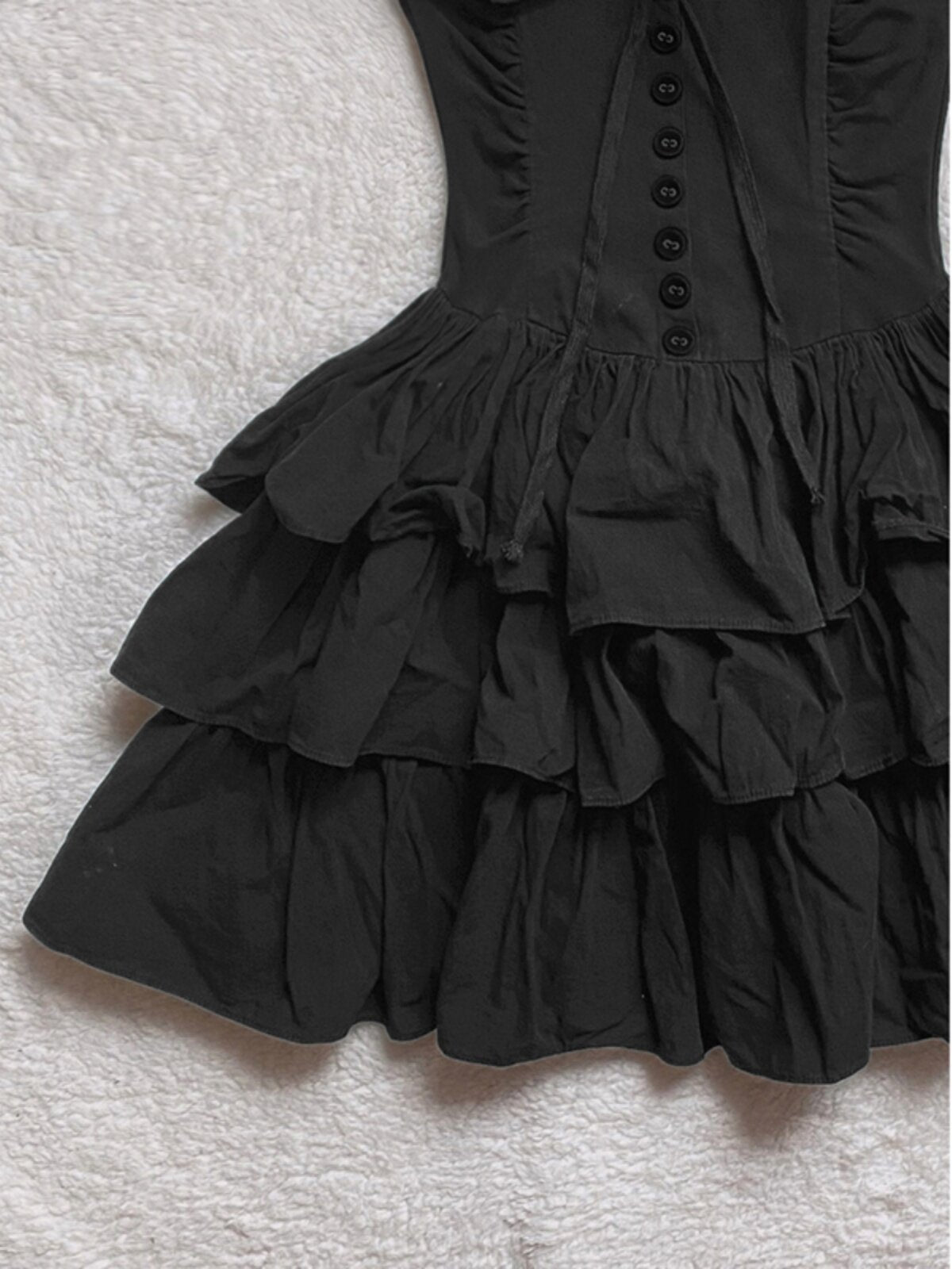 Black tiered ruffle skirt of cake dress with gathered layers and buttoned bodice