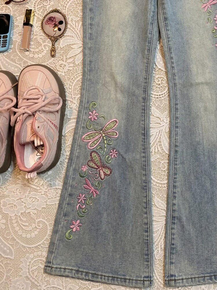 Light blue flared jeans with colorful butterfly embroidery on left thigh and knee.