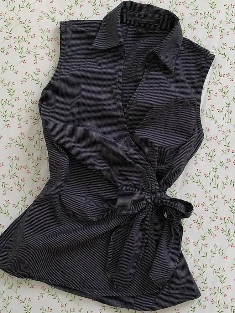 Black sleeveless cardigan top with pointed collar, button placket, and front waist bow
