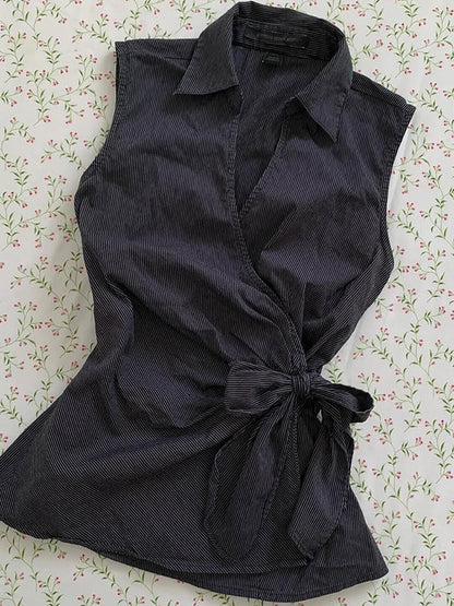 Black sleeveless cardigan top with pointed collar, button placket, and front waist bow
