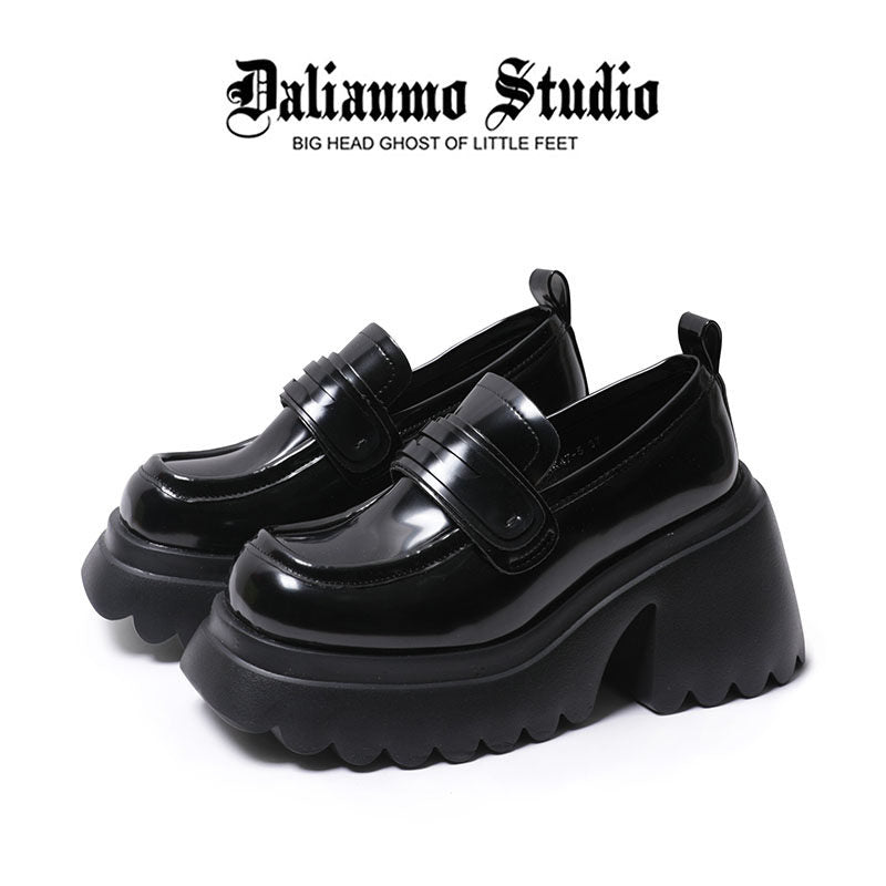 Black platform loafers with glossy finish, strap detailing, and thick lug sole