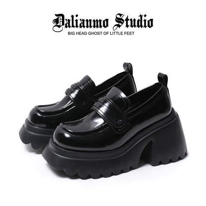 Black platform loafers with glossy finish, strap detailing, and thick lug sole
