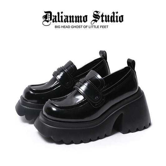 Black platform loafers with glossy finish, strap detailing, and thick lug sole