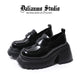Black platform loafers with glossy finish, strap detailing, and thick lug sole