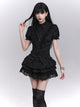 Black puff-sleeve blouse with ruffled button-front and layered ruffle hem