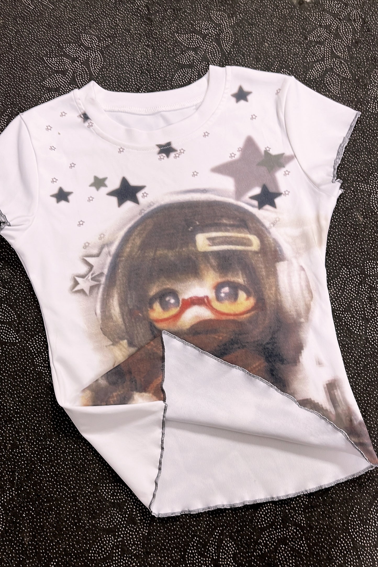 White graphic T-shirt with character portrait and star print, angled hem