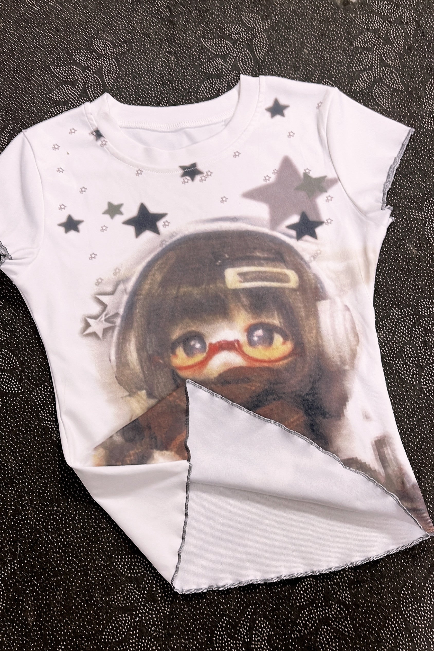 White graphic T-shirt with character portrait and star print, angled hem