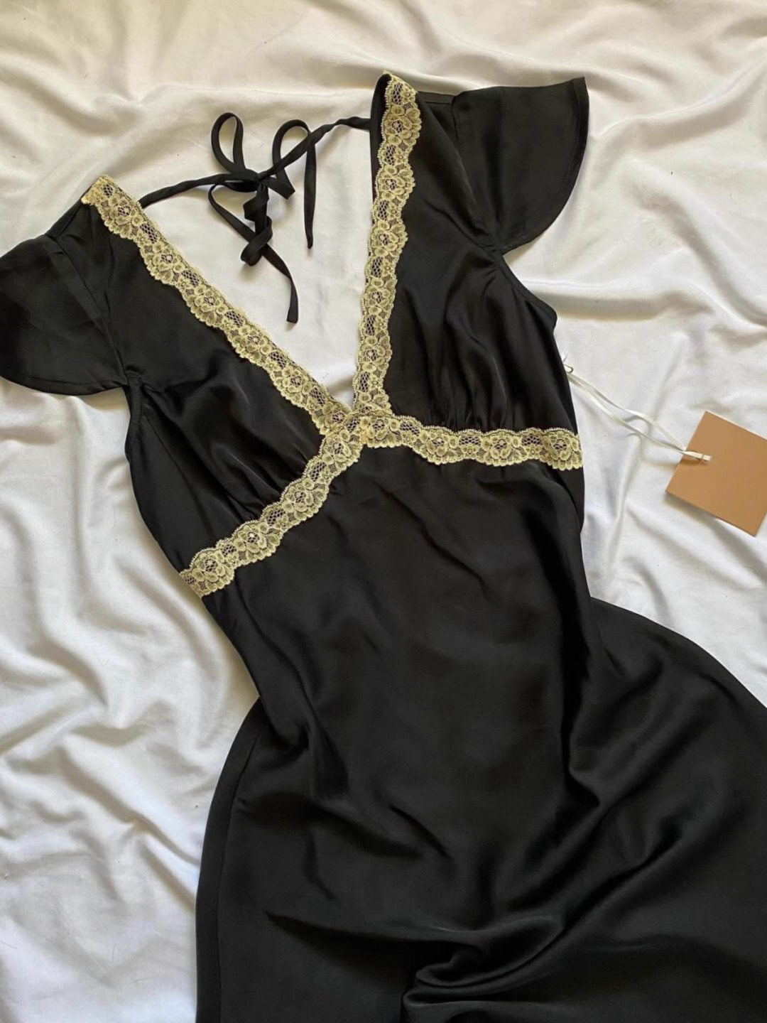 Black lace V-neck mini dress detail: lace trim along neckline, tie-back straps.