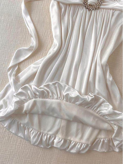 White slip dress detail: pleated bodice, jeweled waist ring, ruffled skirt hem