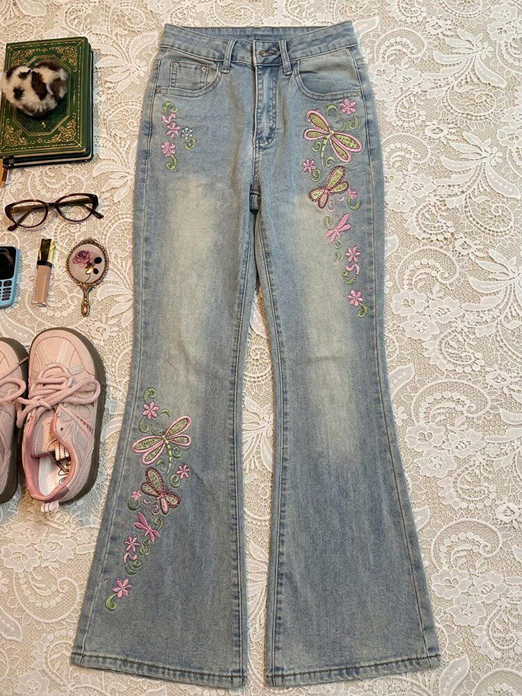 Light blue slim-fit jeans with colorful butterfly embroidery on both legs, zip fly.