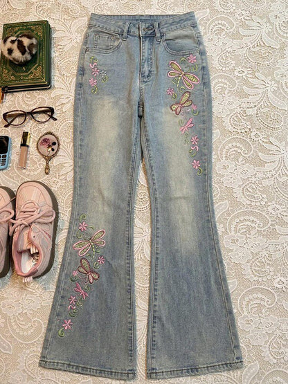 Light blue slim-fit jeans with colorful butterfly embroidery on both legs, zip fly.