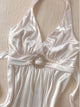 White halterneck slip dress with jeweled belt at waist and draped satin skirt