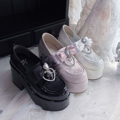 Black glossy platform loafers with ribbon bow and heart charm, plus light pink pair