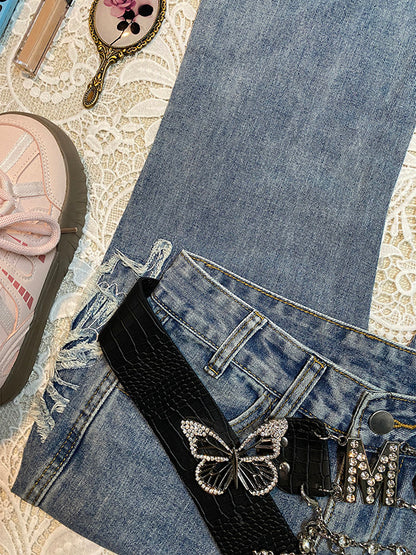 Light-blue denim micro-flare jeans with butterfly embroidery, black ribbon belt, and charms