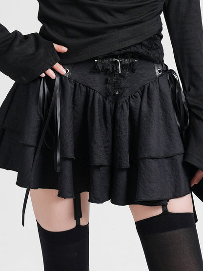 Black layered cake skirt with lace-up waist ties, small studs, and tiered ruffle panels.