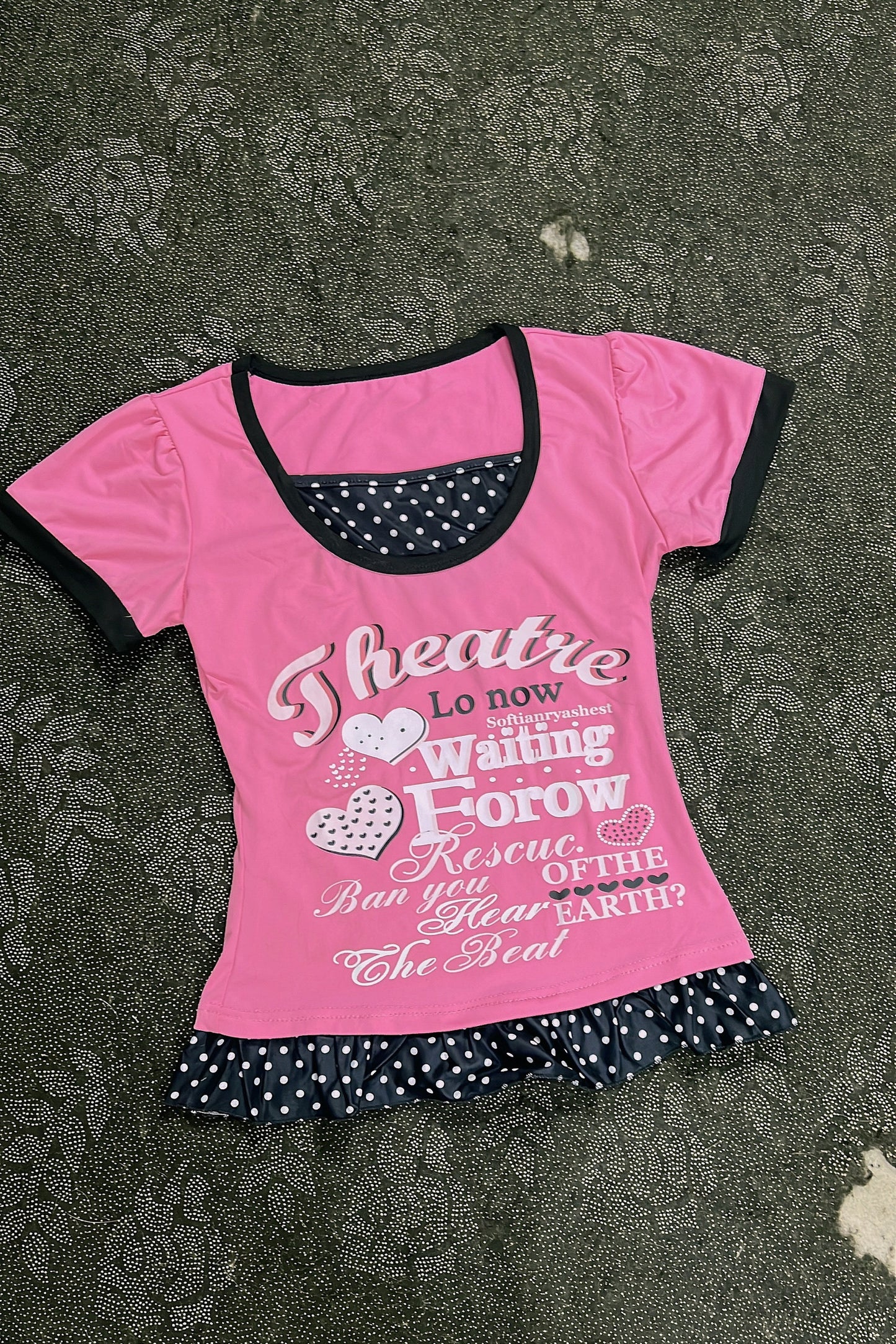 Pink top with black-trim neckline, heart-and-letter graphic, polka-dot ruffle bottom