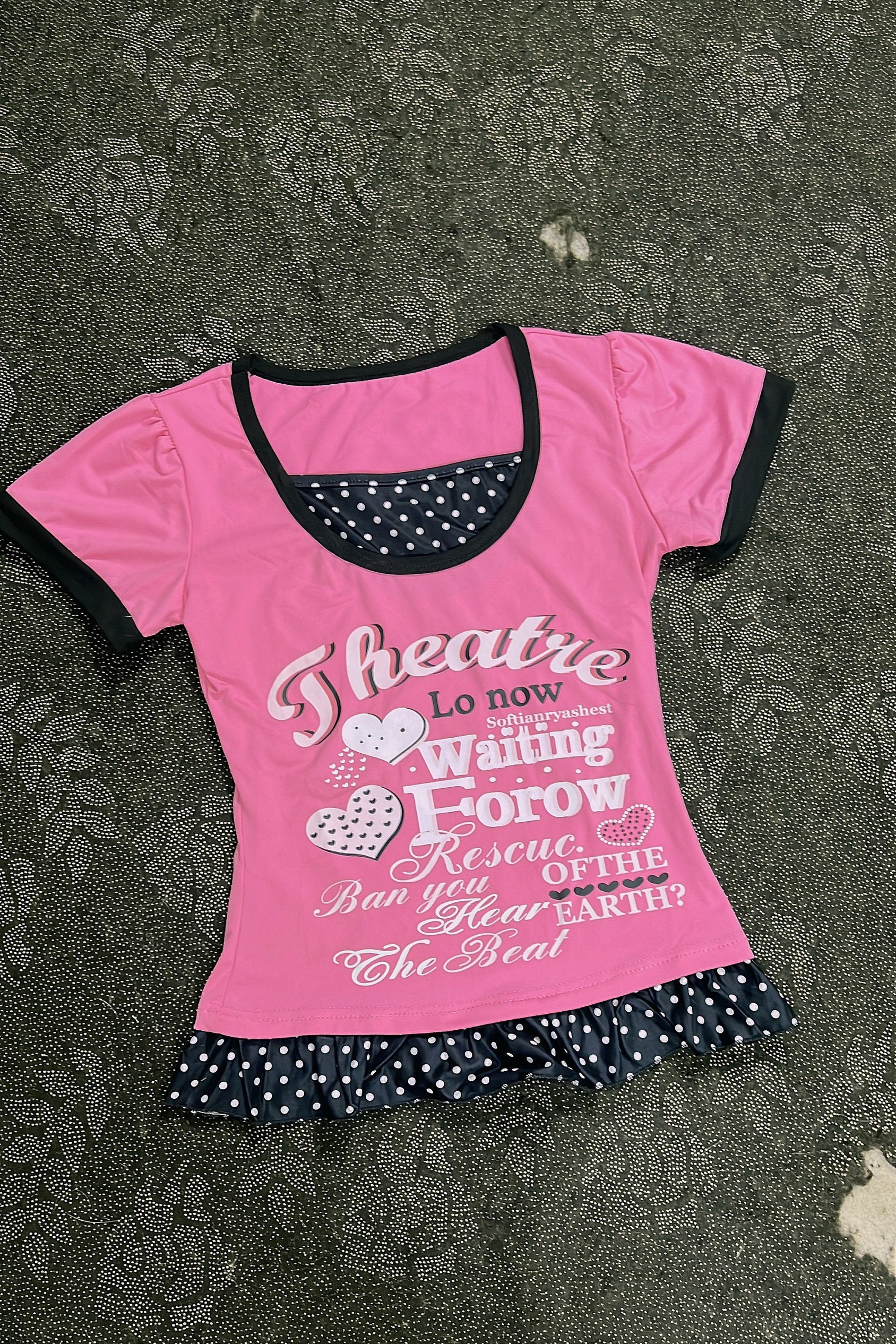 Pink top with black-trim neckline, heart-and-letter graphic, polka-dot ruffle bottom