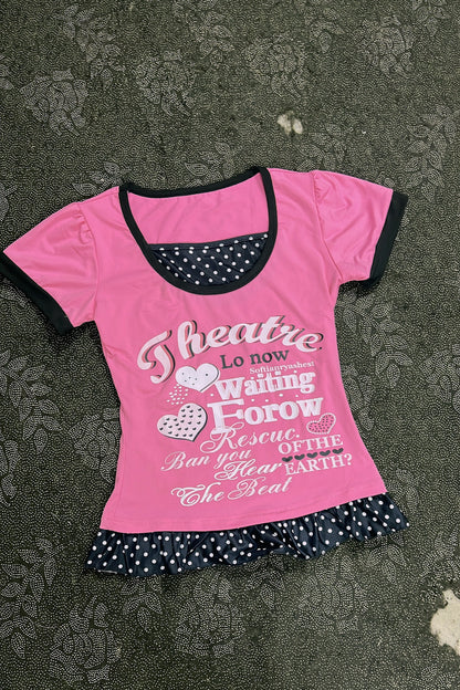 Pink top with black-trim neckline, heart-and-letter graphic, polka-dot ruffle bottom