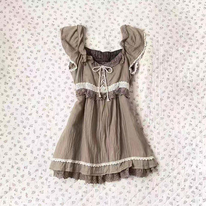 Beige tiered mini dress with lace trim, puff sleeves, and ribbon tie at neckline