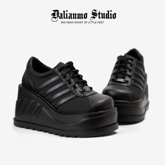 Black platform lace-up sneakers, side view, with striped panels and chunky sole
