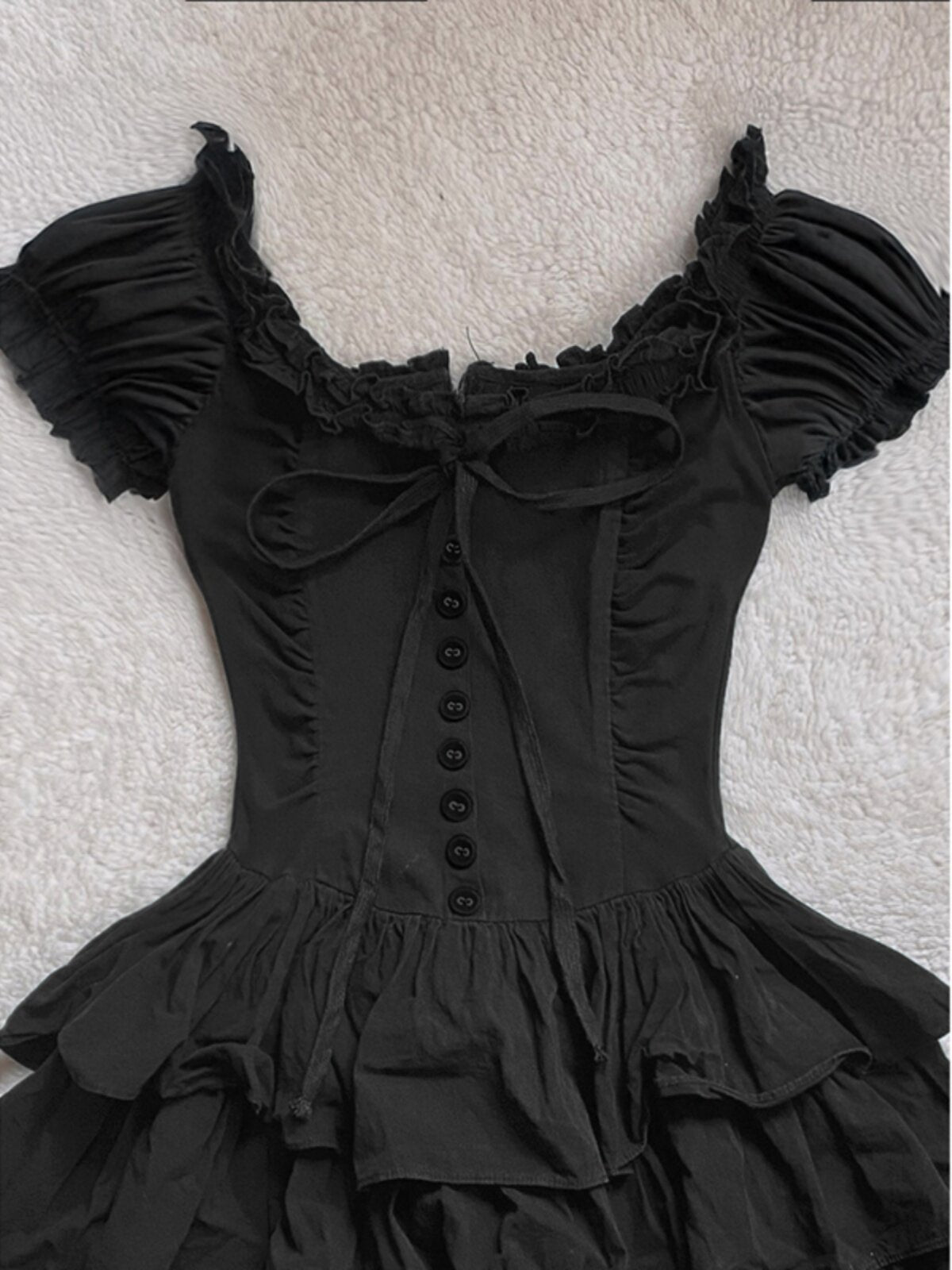 Black off-shoulder cake dress with bow lacing, button placket, and ruffled sleeves