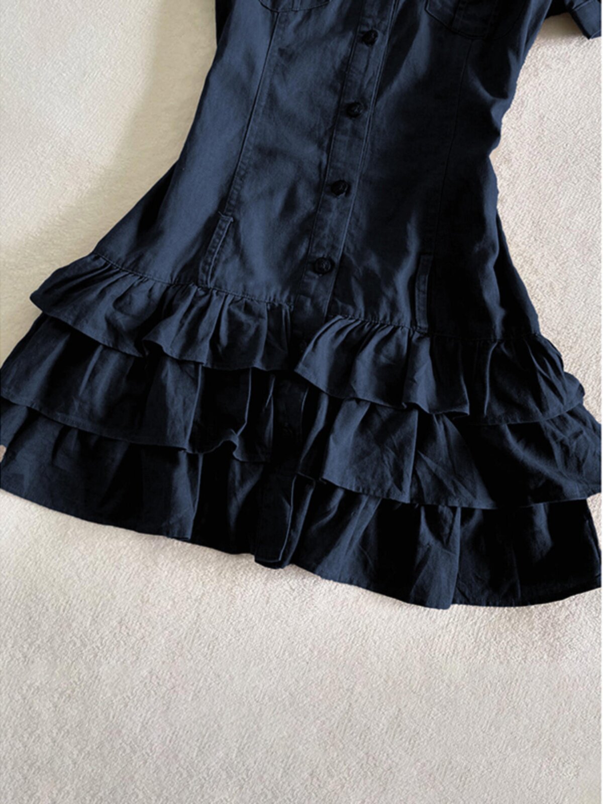 Dark blue tiered ruffle skirt hem on a button-front shirt dress