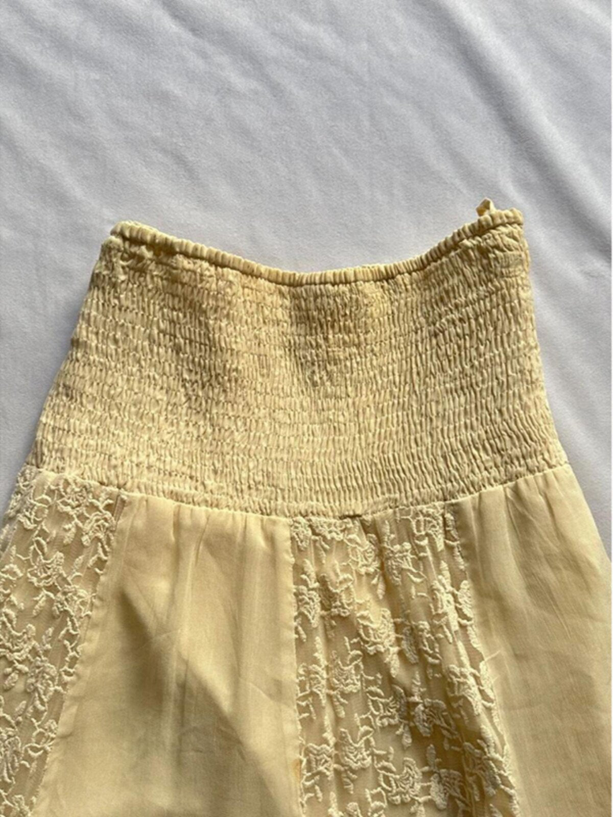 Yellow skirt with smocked elastic waistband, lace patchwork panel, and layered uneven hem
