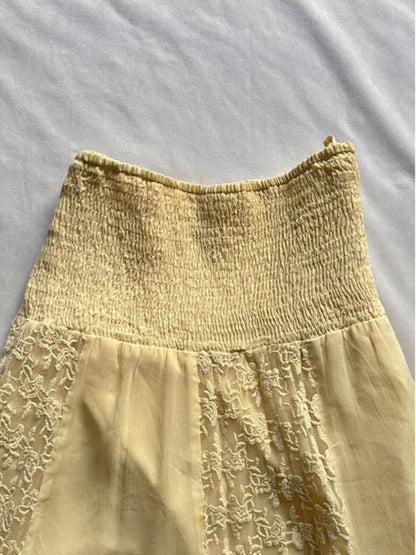 Yellow skirt with smocked elastic waistband, lace patchwork panel, and layered uneven hem