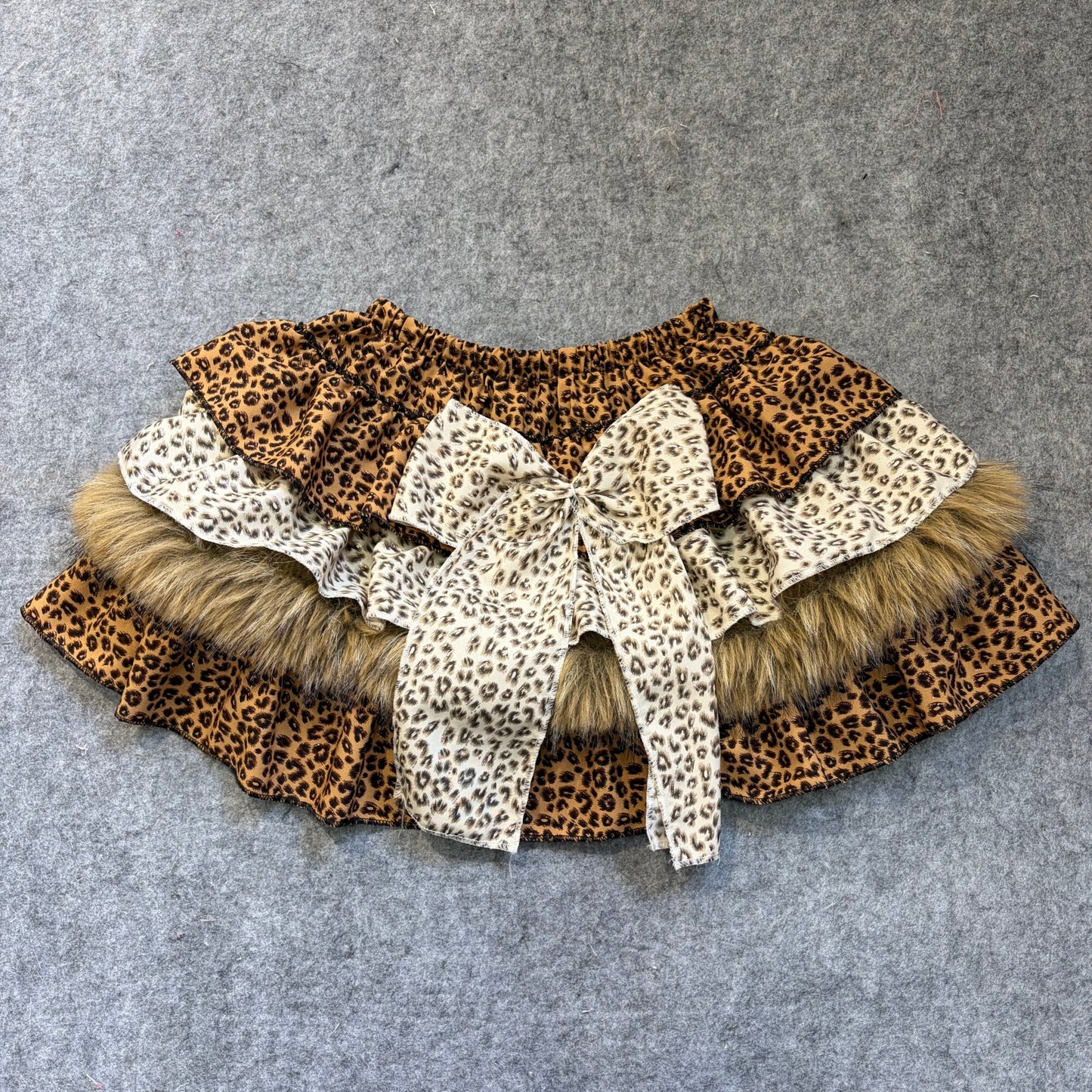 Puffy mini skirt with mixed leopard prints in tan and white, faux fur trim and bow