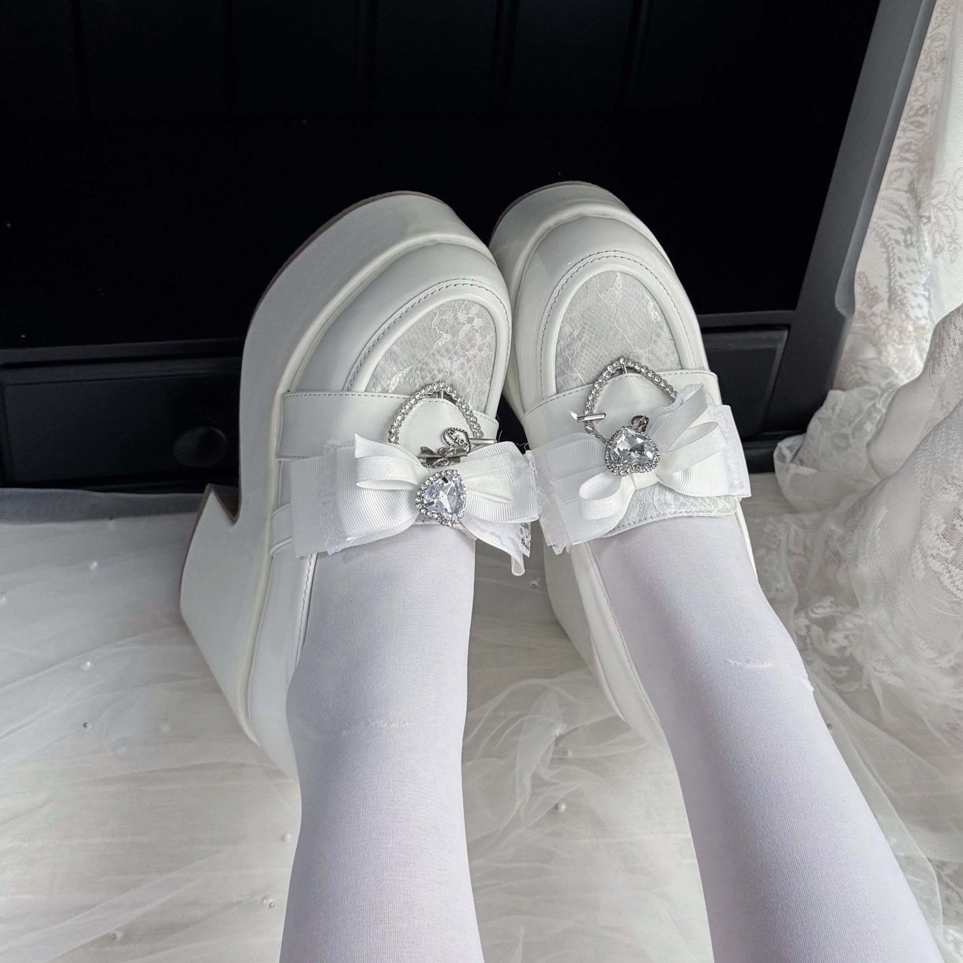 White lace platform loafers with ribbon bows and heart charm accents, side view