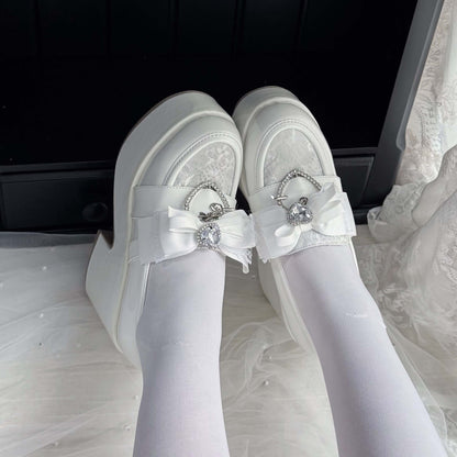 White lace platform loafers with ribbon bows and heart charm accents, side view